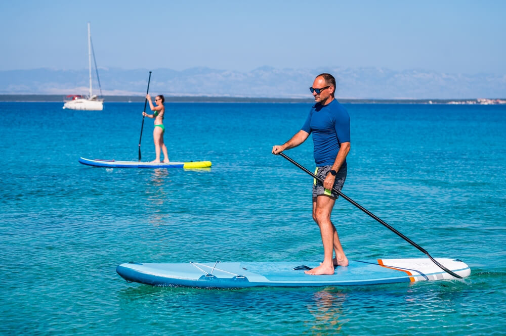 couple riding sup stand paddle in ocean